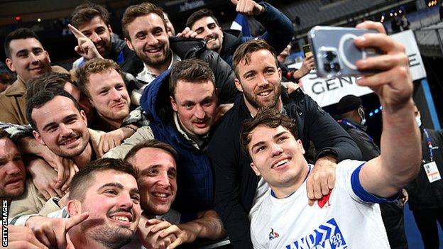 France's scrum-half and captain Antoine Dupont, right, poses for a selfie with fans